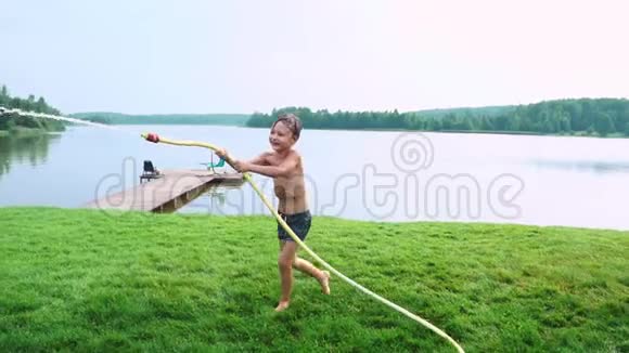 夏天男孩的泳裤向弟弟泼水弟弟在湖边的草地上玩得很开心视频的预览图