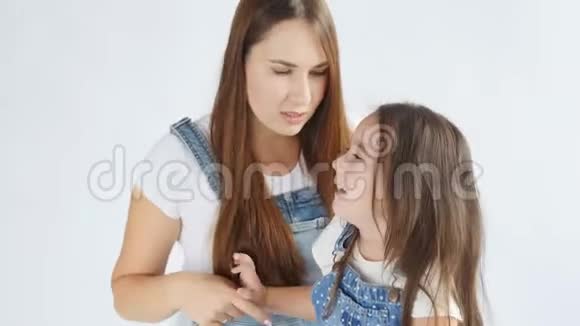 快乐的母亲正在把可爱的女儿的头发梳在白色的内部视频的预览图