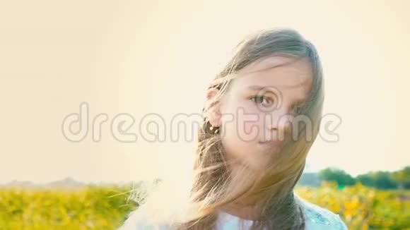 有魅力的小女孩的肖像有一双棕色的大眼睛在大自然的背景下有着发育的头发女孩的微笑和视频的预览图