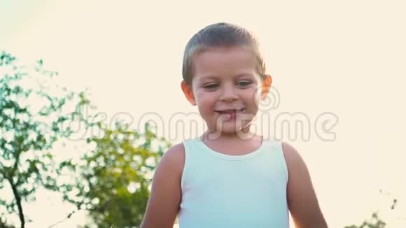一个活泼开朗的孩子在自然背景上的肖像小男孩微笑着看着相机快乐的童年视频的预览图