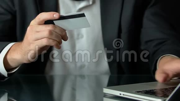 穿西装的男性在笔记本电脑上插入卡号在线购物交易视频的预览图