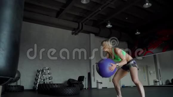 年轻强壮的女人有着完美的健身身材穿着运动服在健身房里用药球运动穿着紧身裤的女孩视频的预览图