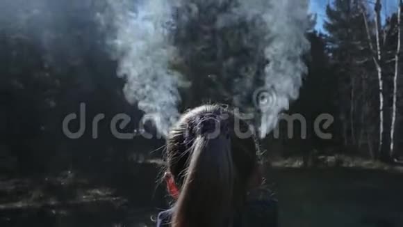 那个女人的头和耳朵里冒出了烟女孩的身后是户外仪式用的陶罐烟灰缸视频的预览图