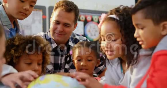白人男教师在教室里教孩子们地球的正面景色视频的预览图