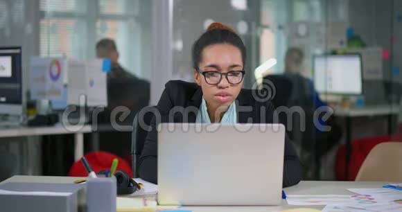 戴眼镜的年轻美国黑人妇女坐在办公室视频的预览图