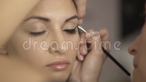 化妆师将化妆霜涂于女孩的眼部区域视频的预览图