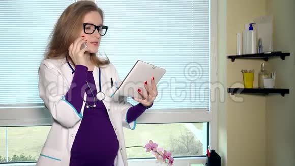 怀孕女医生在电话和平板电脑上交谈视频的预览图