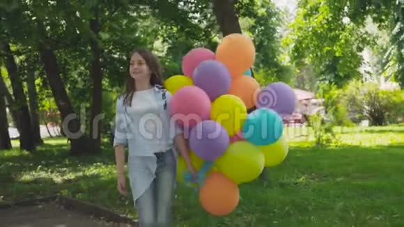 快乐女孩在公园里用气球在镜头前摆姿势和转身的肖像视频的预览图