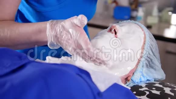 美容诊所年轻女子接受美容治疗在脸上涂抹抗老化液体面膜视频的预览图