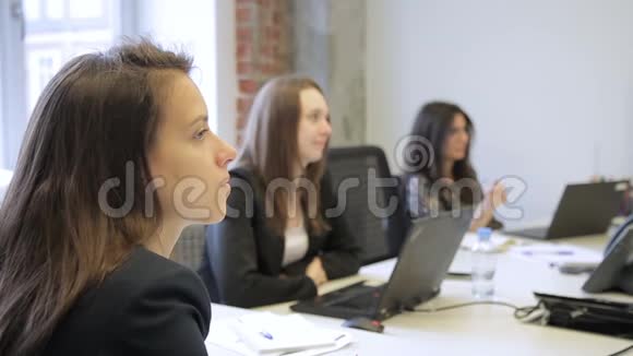 三个女人坐在桌子旁手里拿着笔记本电脑视频的预览图