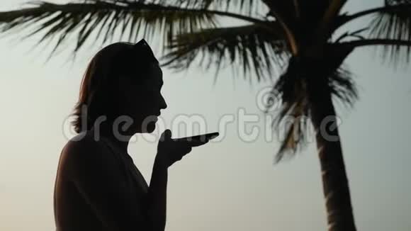 在日落时分年轻的旅游妇女使用手机智能手机音频信息语音识别应用程序ai视频的预览图