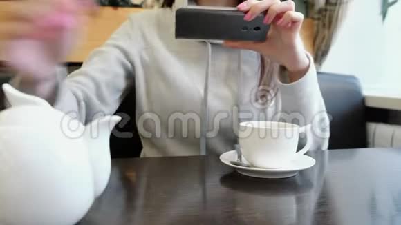 无法辨认的女人她的手照片茶壶和杯在咖啡馆在她的手机视频的预览图