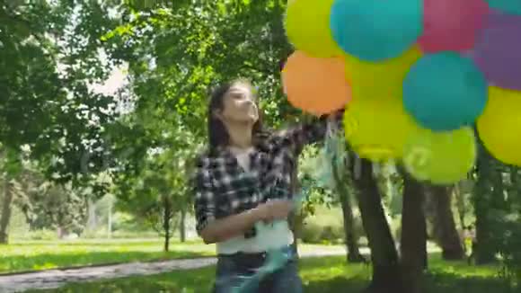 美丽的女孩在阳光明媚的公园里玩彩球的肖像视频的预览图