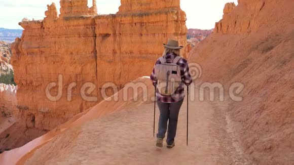 活跃的徒步旅行者女人沿着布莱斯峡谷岩壁附近的路线走视频的预览图