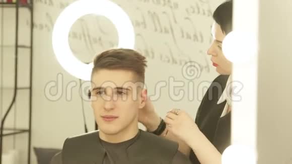 女发型师在美容工作室完成美发前镜后的发型把理发师和男的合拢视频的预览图