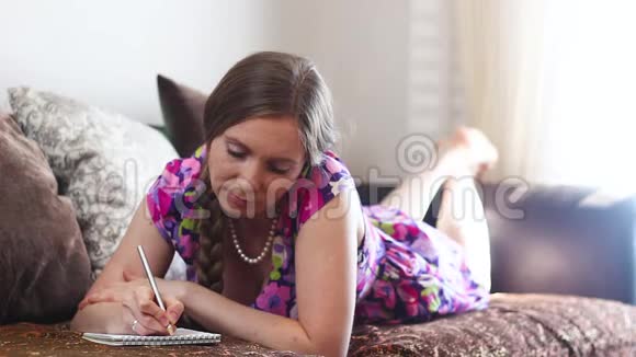 年轻女子躺在沙发上做笔记视频的预览图