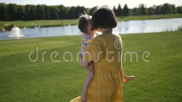 妈妈在绿色草地上打转小女儿视频的预览图