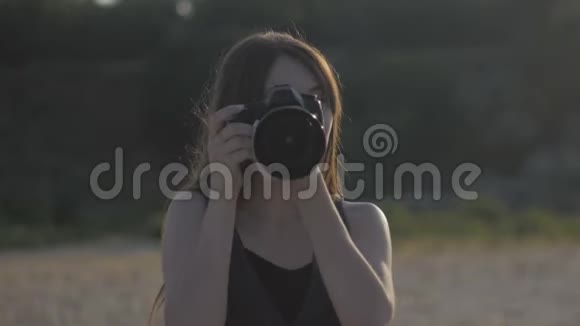 女摄影记者用专业相机拍摄大自然的照片女孩在拍镜头看着视频的预览图