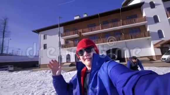 一个年轻人看着镜头头上戴着一支长矛喜欢冬天的雪山穿着蓝色滑雪板视频的预览图
