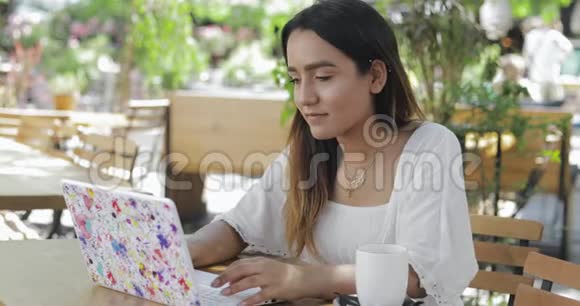 坐在户外自助餐厅工作的女人视频的预览图