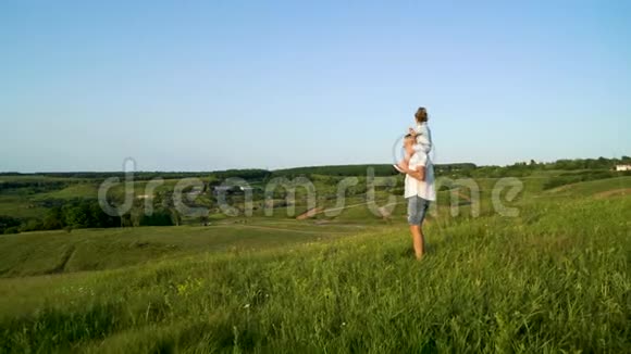父亲和女儿在草地上共同散步视频的预览图