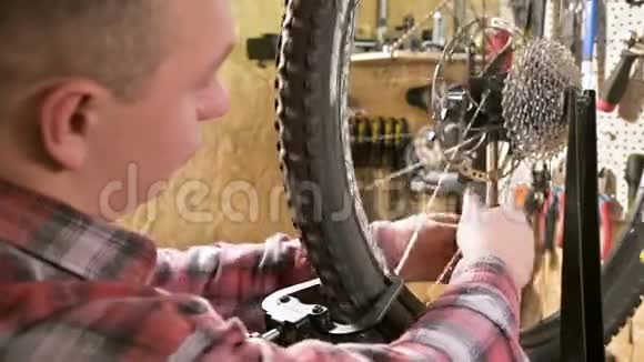 年轻的男自行车修理工在车间的一个支架上用专门的扳手拧紧车轮的辐条视频的预览图