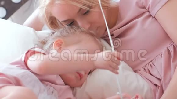 小可爱的金发女孩和她妈妈一起玩巴伦她穿着粉红色的裙子躺在床上视频的预览图