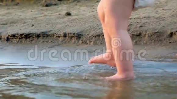 妈妈他的手牵着孩子在海滩上孩子的脚上水慢动作快关门视频的预览图