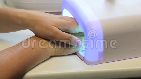 女人做指甲在紫外线灯中烘干清漆视频的预览图