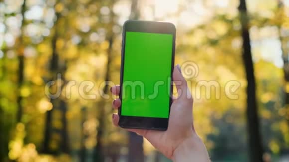 女孩显示手机绿色屏幕户外城市环境女士手拿智能手机与色度键背面视频的预览图
