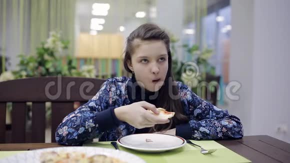 在咖啡馆吃披萨的女孩一个在披萨店的少年正在吃晚饭视频的预览图