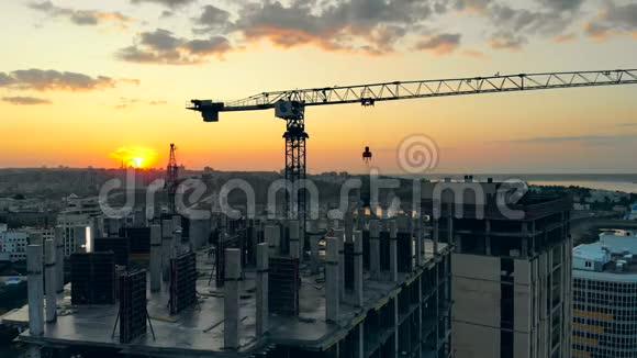 一台起重机在日落背景下在施工现场工作视频的预览图