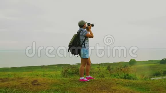 一个背着背包的女人在山上拍了一张湖的照片视频的预览图