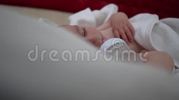 一个带瓶子的婴儿躺在床上床上铺着白色的床上用品动作缓慢视频的预览图