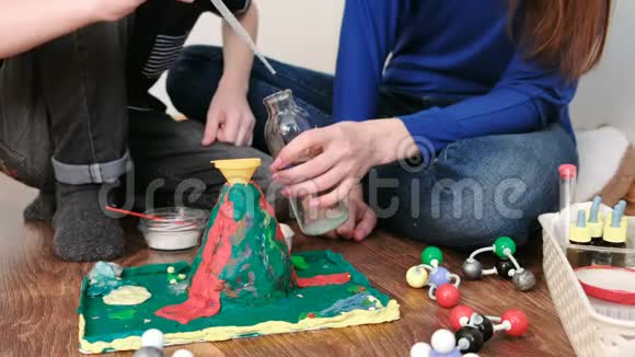 化学实验男孩的特写镜头他用一只手把瓶子里的水倒进了火山的漏斗视频的预览图