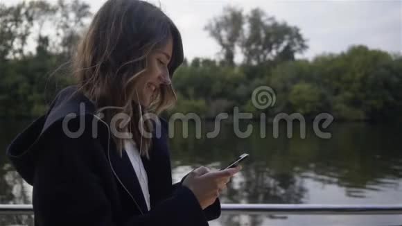 从侧面看一个女人听音乐在河边散步视频的预览图