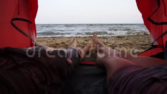悠闲的尤格夫妇在帐篷里休息眺望大海双脚特写视频的预览图