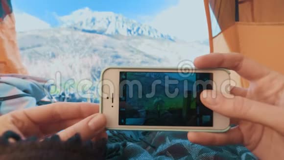 露营妇女躺在帐篷里用智能手机拍照脚贴身女孩穿着登山靴放松视频的预览图