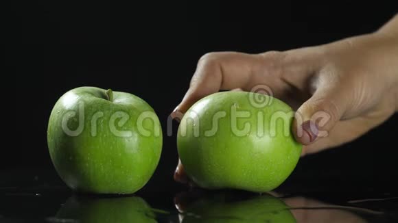 黑桌子上的绿苹果水果黑色背景手拿起苹果近距离射击视频的预览图