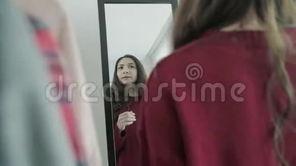 一幅美丽迷人的亚洲女人梳头在家里的更衣室里挑选衣服的肖像视频的预览图