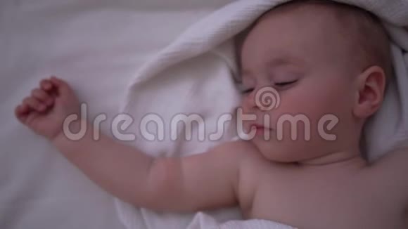 一个可爱的婴儿睡在大床上床上有白色的亚麻布动作缓慢视频的预览图