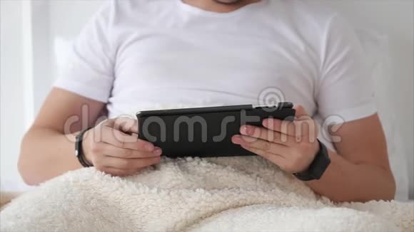 男人在床上用平板电脑放松视频的预览图