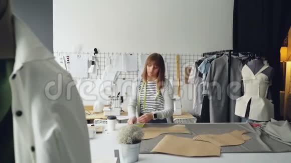 迷人的裁缝师是测量服装纸模板躺在工作室的桌子上用卷尺女人很冷静视频的预览图