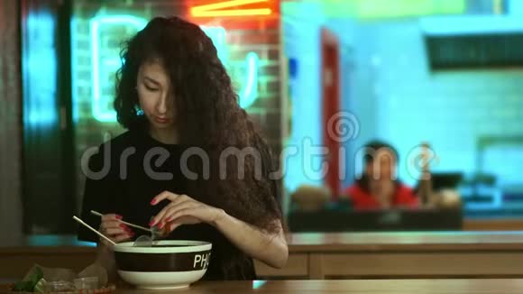 一个可爱的年轻亚洲女孩正在亚洲咖啡馆里吃PHO汤用中国筷子吃面条中文视频的预览图