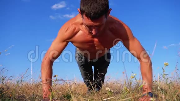 裸露躯干的年轻运动员在大自然中拍俯卧撑慢动作视频的预览图