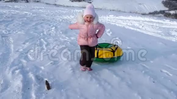 一个小女孩在雪地里奔跑拉着她的管子视频的预览图