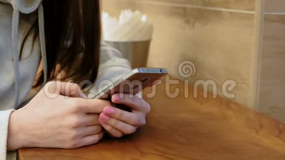 坐在咖啡馆里一个穿着亮色衬衫的女人在手机里发信息视频的预览图