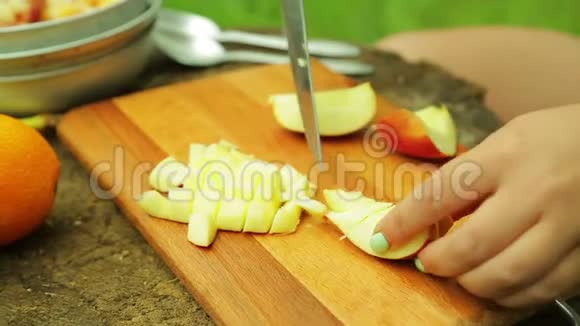 女人的手在切片上切苹果在露天吃水果沙拉视频的预览图
