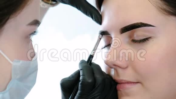 美容师用刷子在客户眉毛上涂油漆特写前景眉毛矫正视频的预览图