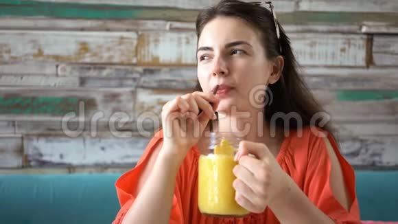 小姑娘喝着新鲜的热带芒果奶昔视频的预览图